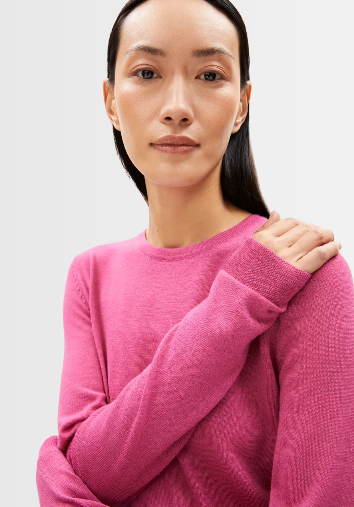 Model trägt den Eldiaa Merino Pullover in leuchtendem Pink, aus extra feiner Bio-Merinowolle, der sich angenehm weich anfühlt und eine schlanke Silhouette betont.
