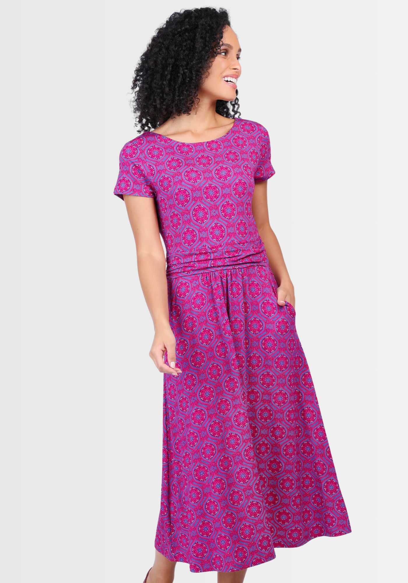 Lifestyle-Aufnahme des Kleids „Malind mandala“ in Himbeerrot, getragen mit Sandalen und dezenten Accessoires. Der schwungvolle Rock, die Eingrifftaschen und der leichte U-Boot-Ausschnitt setzen lässige Akzente und verleihen dem Outfit eine feminine Note.