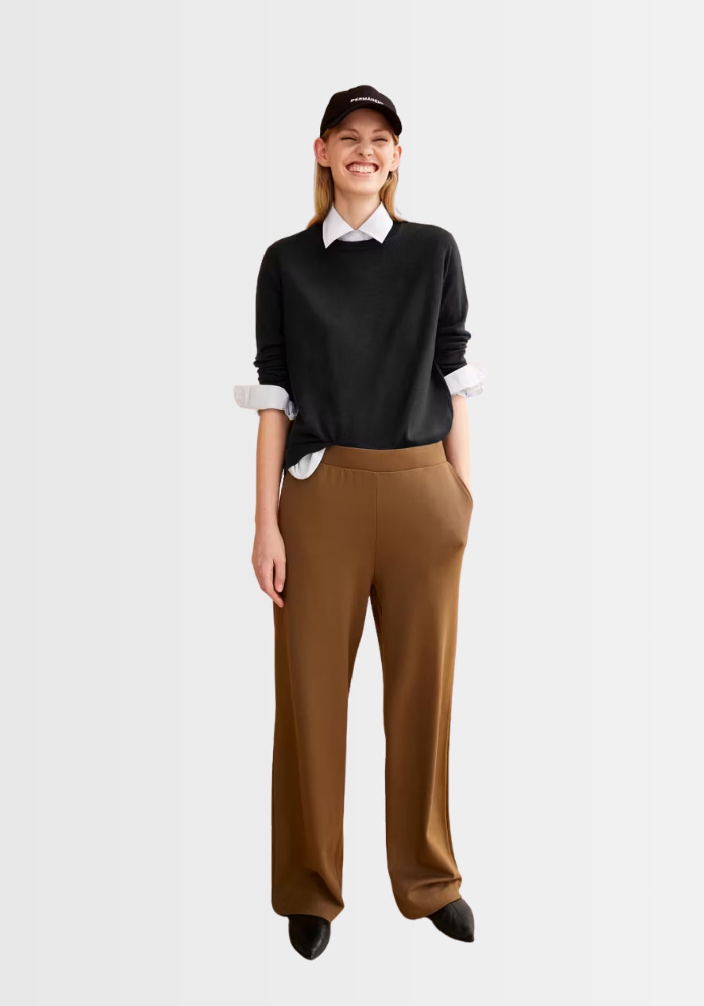 Model trägt den locker geschnittenen Larunaa Sweater in Schwarz, kombiniert mit einer weiten Hose und Hemd für einen lässig-eleganten Alltagsstil.