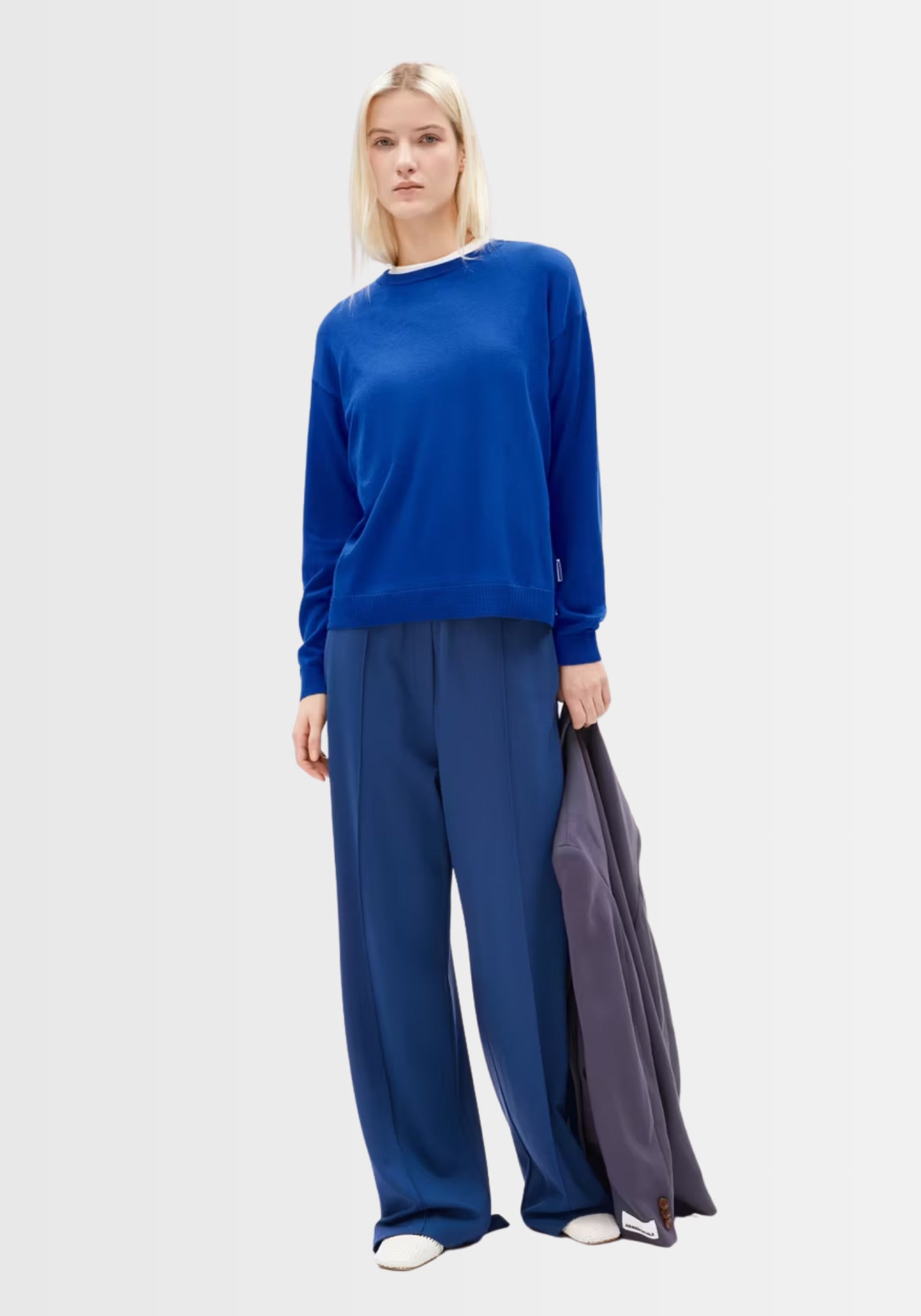 Model präsentiert den Larunaa Sweater in lapis blue in einem urbanen Freizeit-Look, kombiniert mit Jeans und Sneakern – nachhaltig, bequem und modisch.