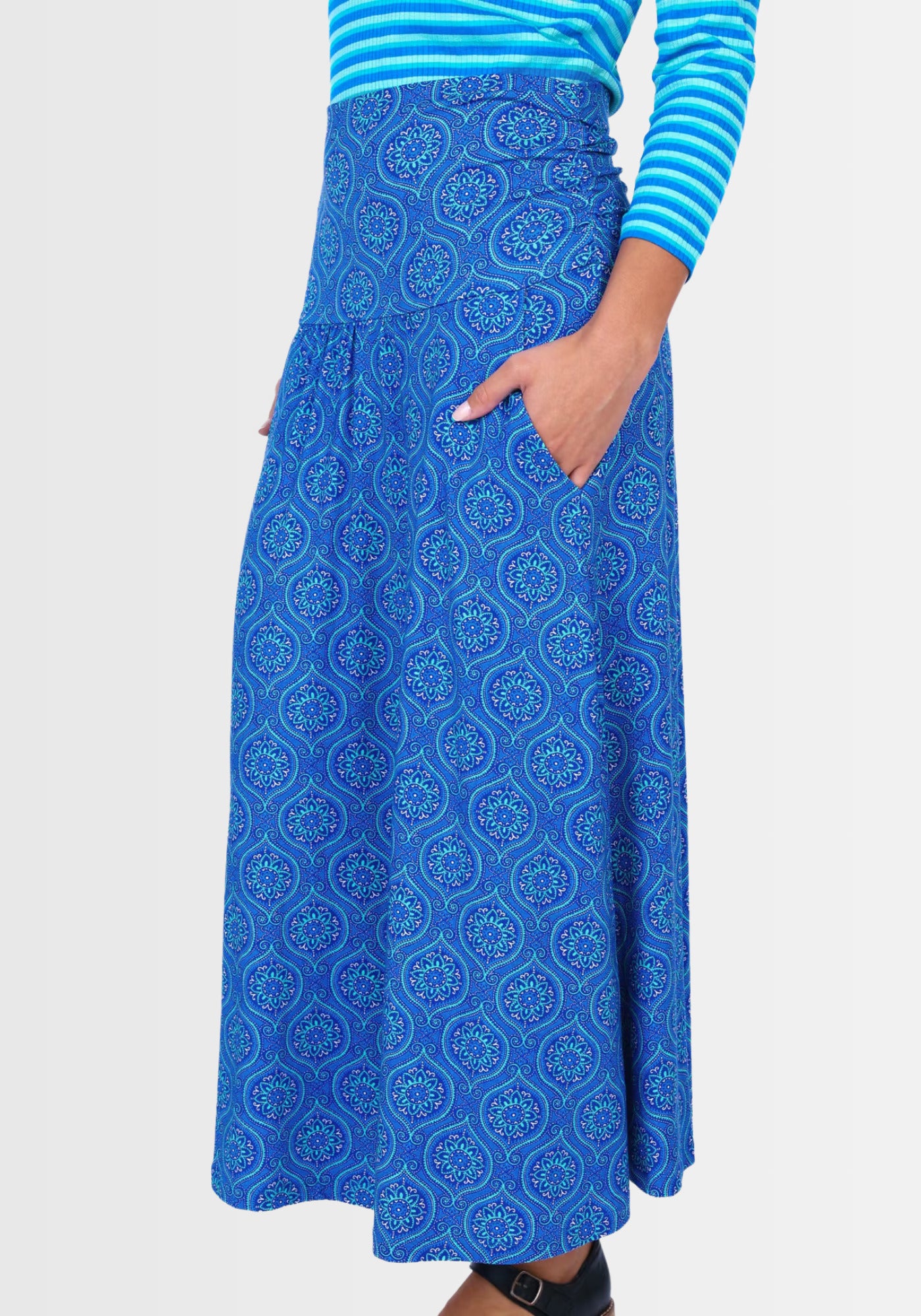 Seitenansicht des Rocks „Kalla“ in Lapiston, der durch praktischen Eingrifftaschen besticht. Das ornamental inspirierte Design und das elastische Material aus LENZING™ ECOVERO™ Viskose garantieren hohen Tragekomfort und Bewegungsfreiheit.