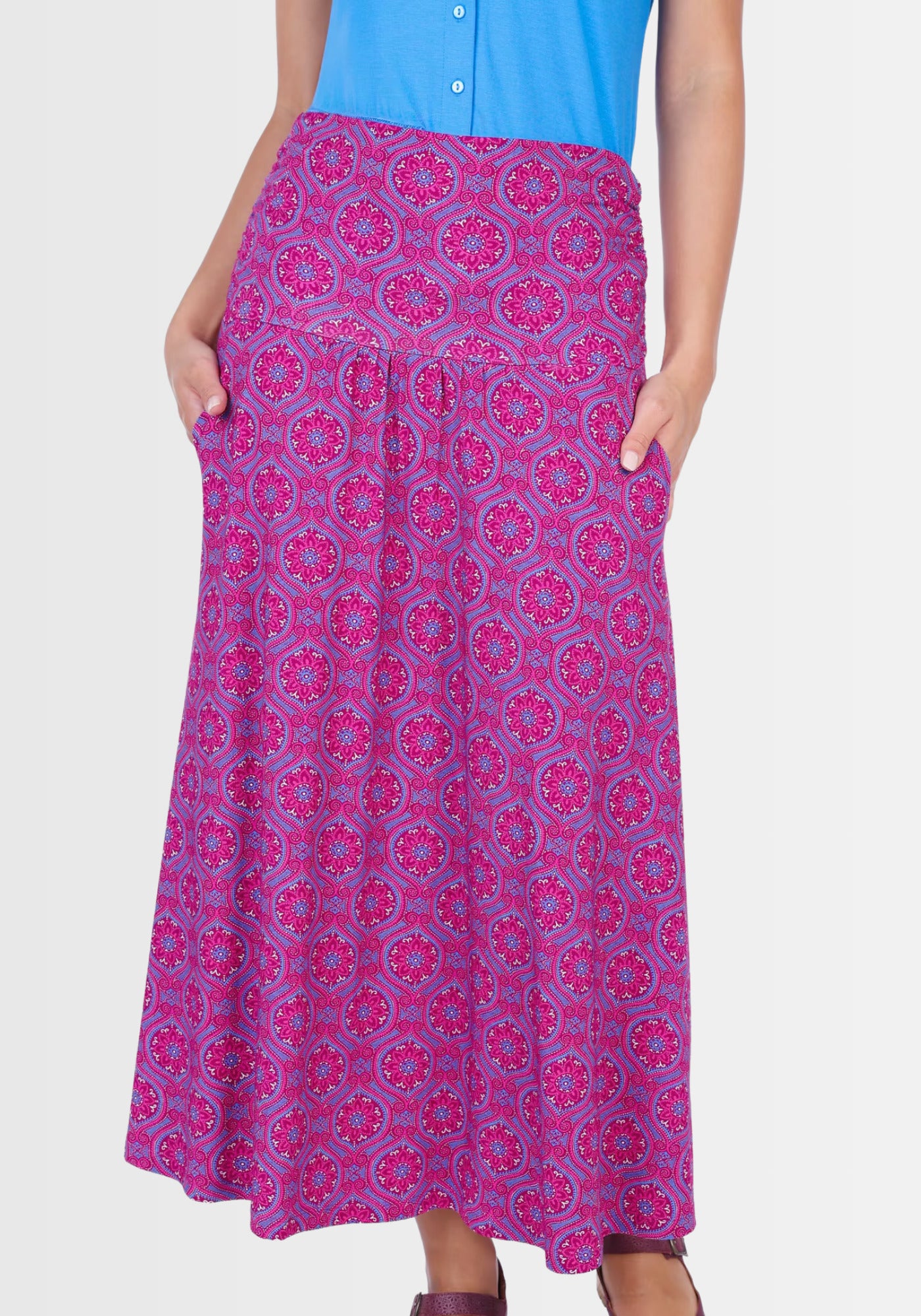 Ein Model trägt den Rock „Kalla“ in Himbeerrot. Der umschlagbare Bund schmiegt sich bequem an die Taille an, während der ornamentale Druck und die leichte A-Linie für eine feminine Silhouette sorgen.