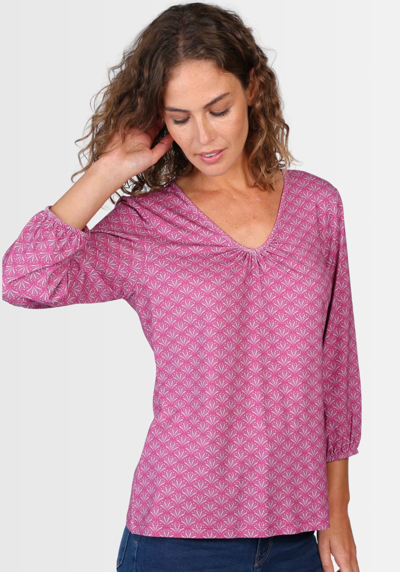 Lifestyle-Aufnahme des Shirts „Andria“ in sattem Himbeerrot, kombiniert mit Jeans und Sandalen. Der lockere Schnitt, das geraffte Dekolleté und die bequemen 3/4-Ärmel machen es zum perfekten Begleiter für jeden Tag.