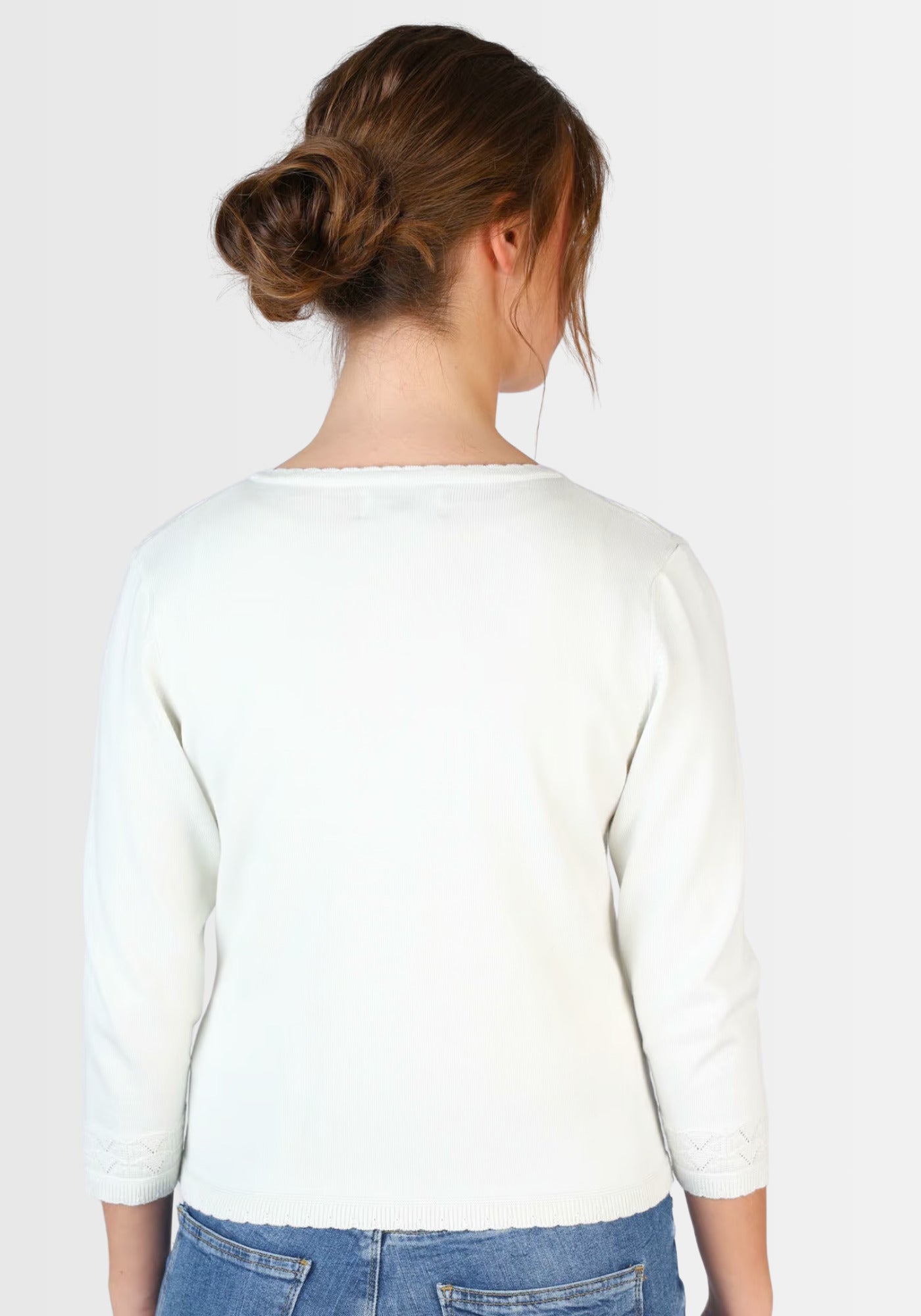 Rückansicht der kurzen Strickjacke „Liselotte“ in Weiß. Das dezente Ajourmuster und die sorgfältige Verarbeitung aus nachhaltiger Bio-Baumwolle sorgen für einen zeitlosen, femininen Look.