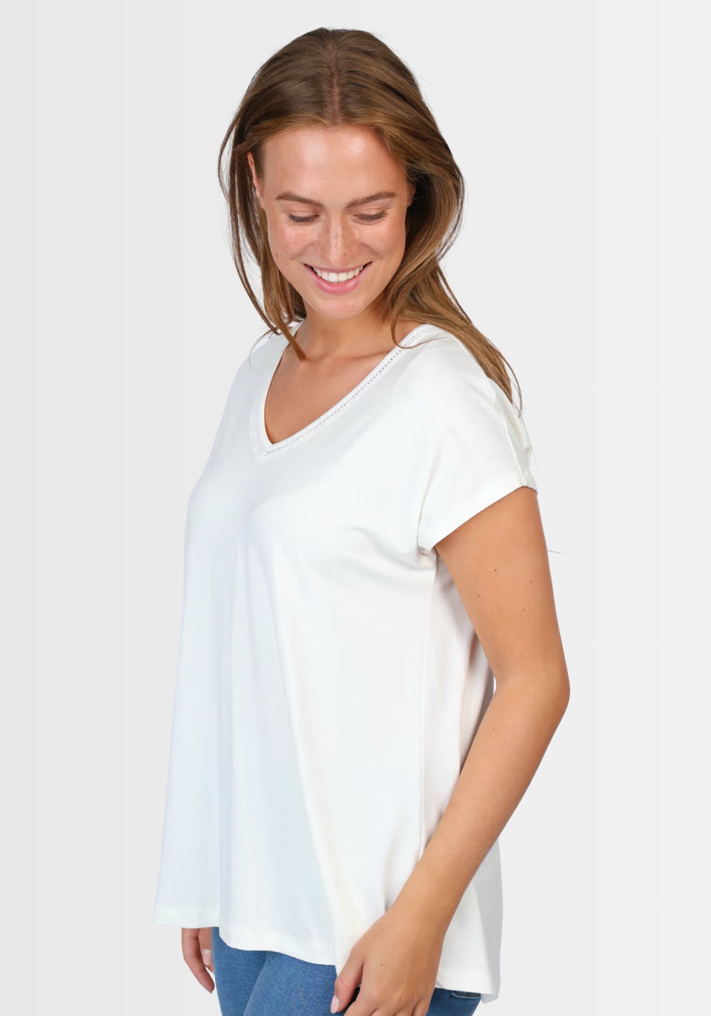 Seitenansicht des T-Shirts „Nylara“ in Ivory, das durch seinen entspannten, locker geschnittenen Stil und leicht überschnittene Arme überzeugt – ein echtes Sommer-Must-Have für jeden Kleiderschrank.