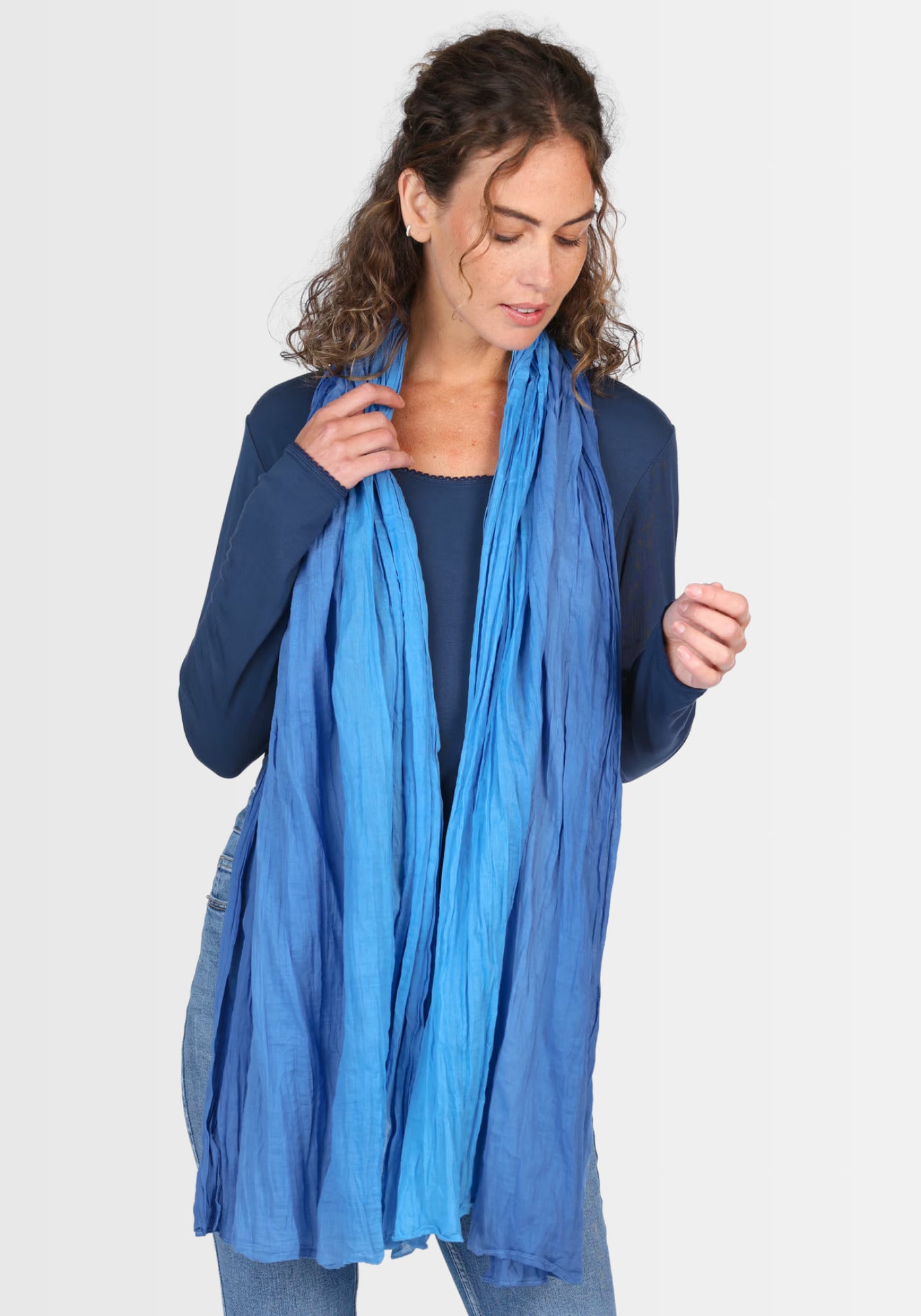 Frau legt sich das Tuch „Asta“ als Stola über die Schultern. Die leichte Baumwollqualität in leuchtendem Lapis-Blau verleiht jedem Outfit einen frischen Akzent.