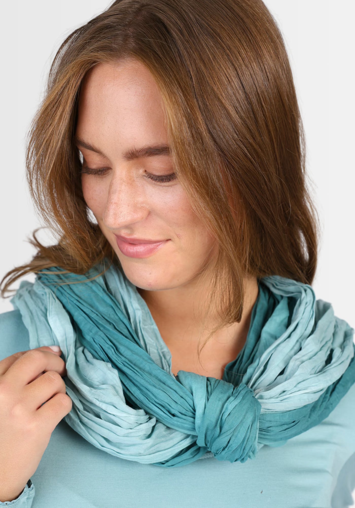 Ein Model präsentiert das Tuch „Asta – Mermaid“ in Blau, das durch seinen einzigartigen, sanften Farbverlauf und die hochwertige Baumwollqualität einen frischen, maritimen Look verleiht – perfekt kombinierbar zu Kleidern und Röcken.