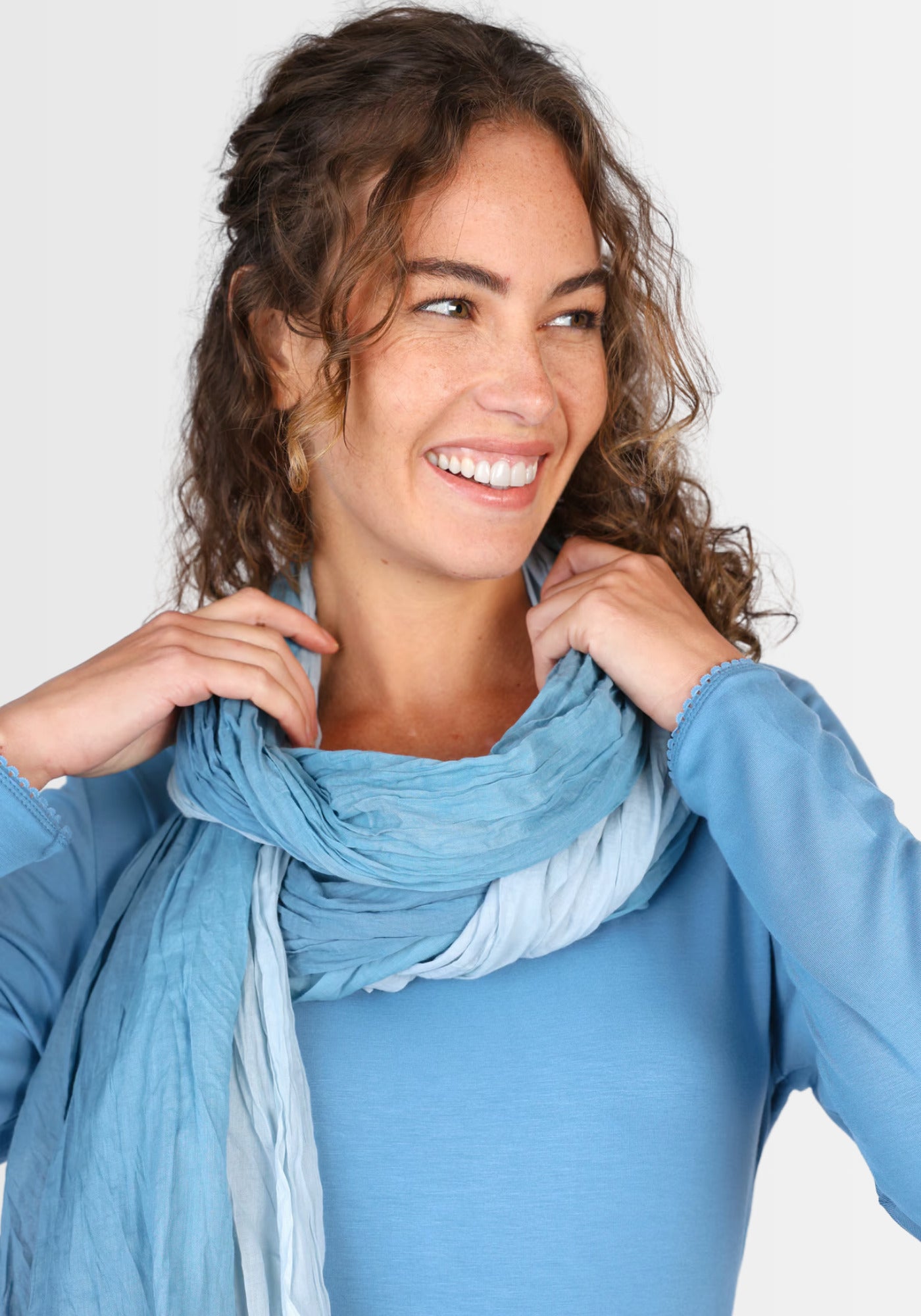 Ein Model präsentiert den „Asta – Swedish Blue“ Baumwollschal in einem stilvollen Outfit. Der Schal überzeugt mit seinem sanften Farbverlauf und verleiht dem Look einen frischen, skandinavisch inspirierten Touch.