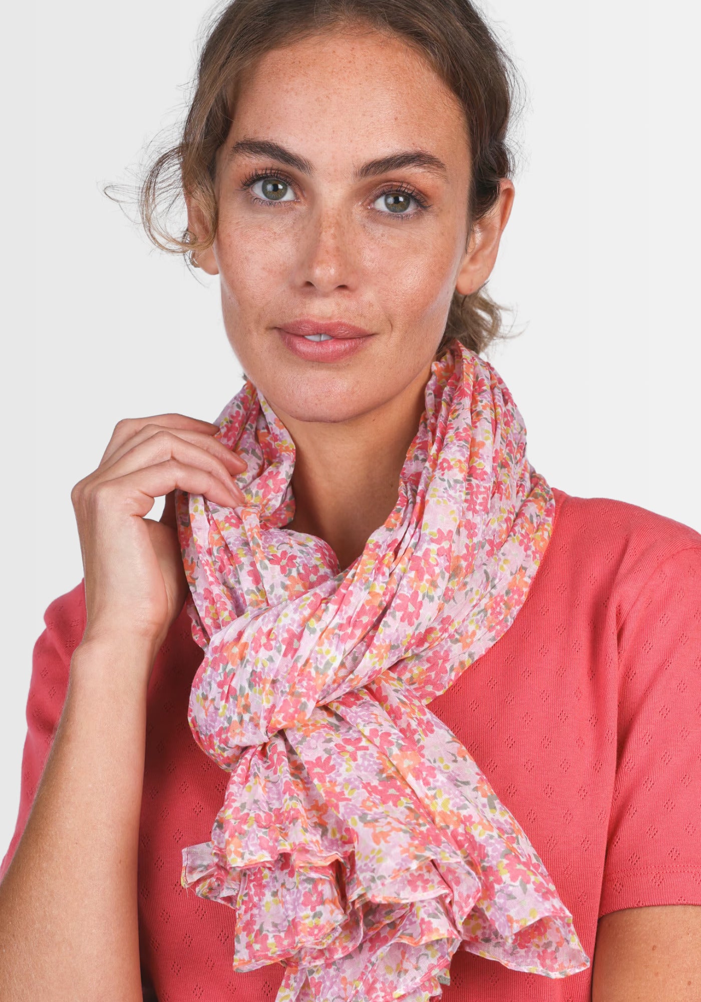 Ein Model trägt das Tuch „Inesse – rose“ von Sorgenfri Sylt, das durch seinen feinen, floral bedruckten Stoff in zartem Rosa einen femininen, eleganten Akzent setzt – perfekt kombinierbar zu Kleidern und Röcken.