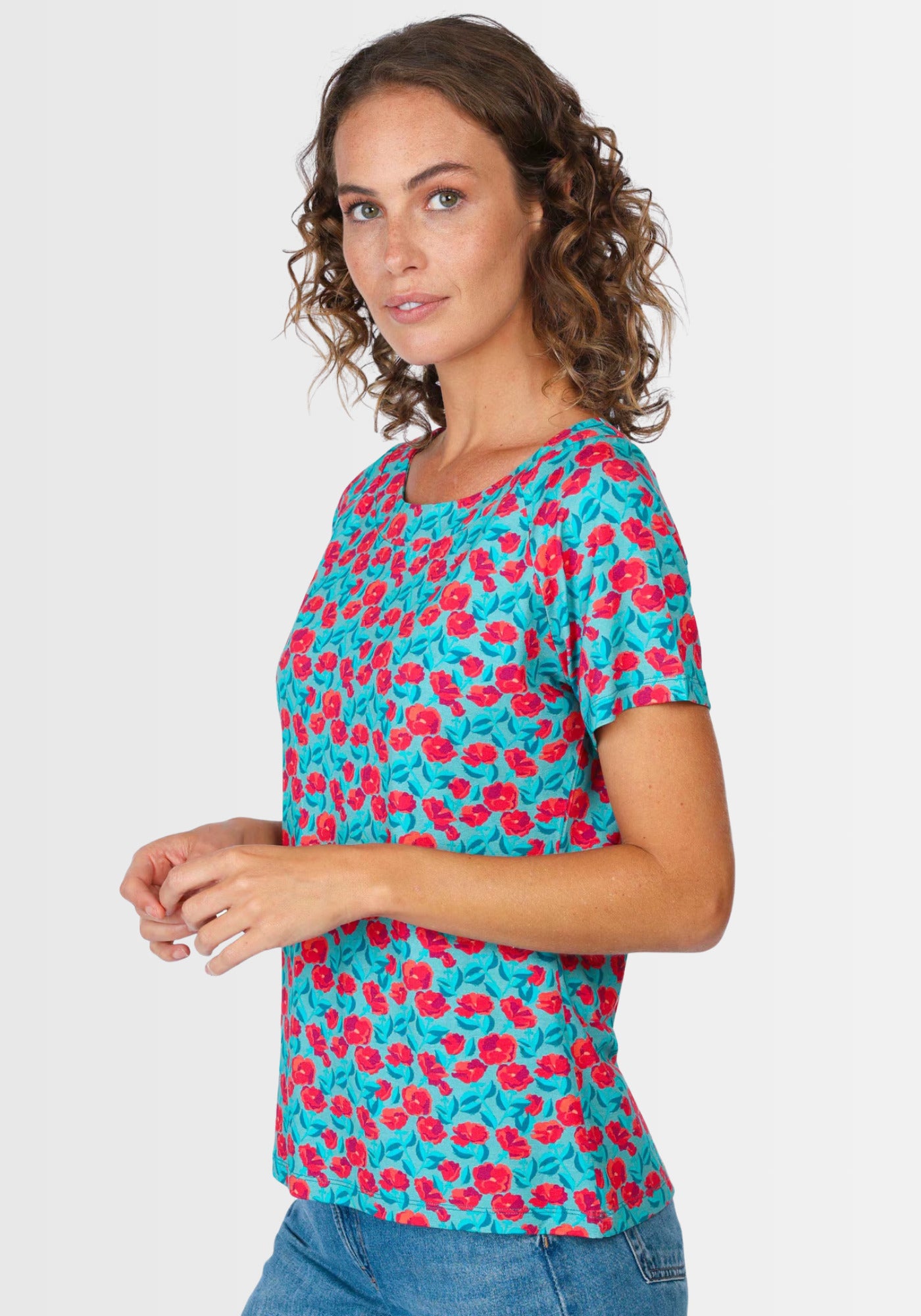 Seitenansicht des floralen T-Shirts „Zoe rosy“ in Türkis. Dank der nachhaltigen Viskose-Elasthan-Qualität und dem Raglanarm bietet es einen luftigen, bequemen Sitz für jede Figur.

