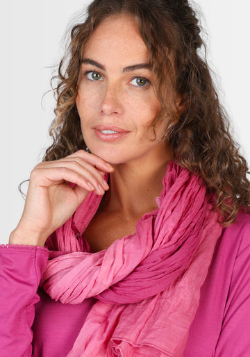 Ein Model präsentiert den Tuch Asta – raspberry, getragen als modisches Highlight. Der Bio-Baumwollschal überzeugt durch seinen zarten, harmonischen Farbverlauf und passt perfekt zu Kleidern und Röcken.