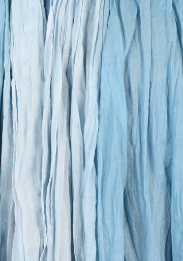 Detailaufnahme der feinen, weichen Baumwollstruktur des Tuchs „Asta – Swedish Blue“. Der dezente Farbverlauf und die hochwertige Verarbeitung machen es zu einem eleganten, alltagstauglichen Accessoire.

